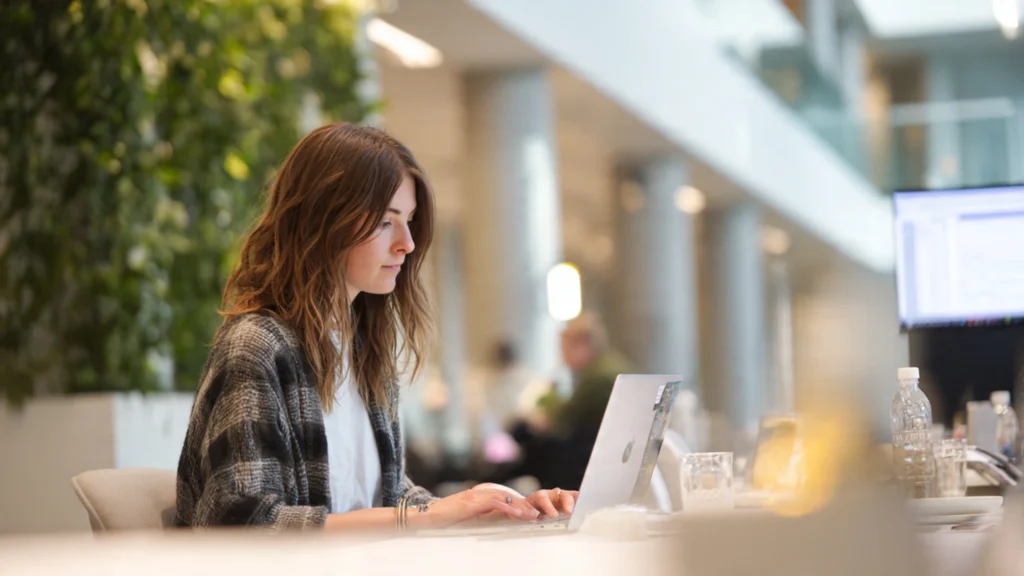Young researcher working at a laptop in a bright modern Stockholm office representing the SEI intern experience